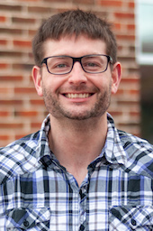 A headshot of Kyle O'Donnell in a plaid shirt.