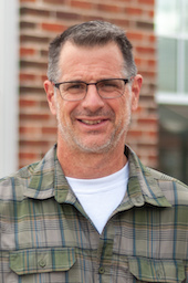 A headshot of J. Fred Rhoderick in a plaid shirt.