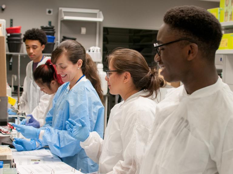 Students working in the lab beside one of their postdoc mentors.