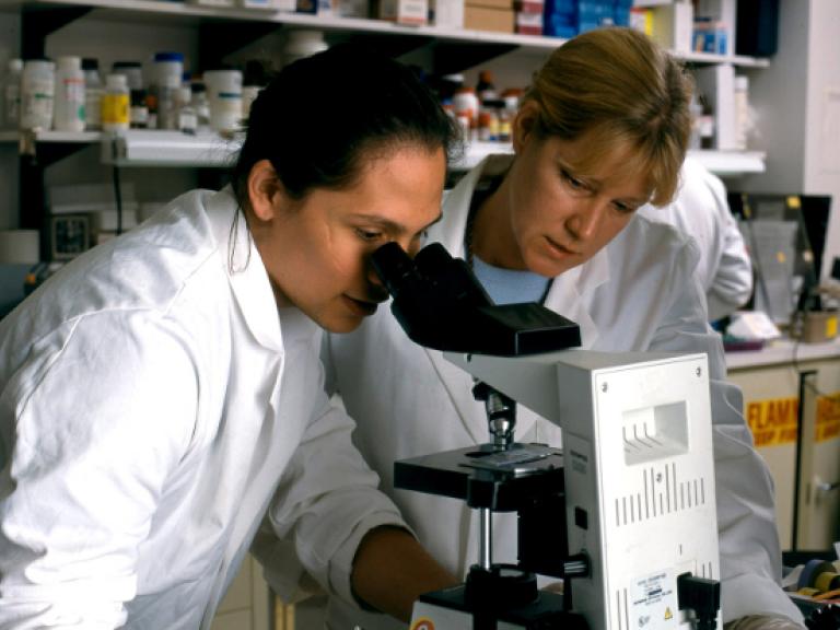 Two female scientists looking though microscope