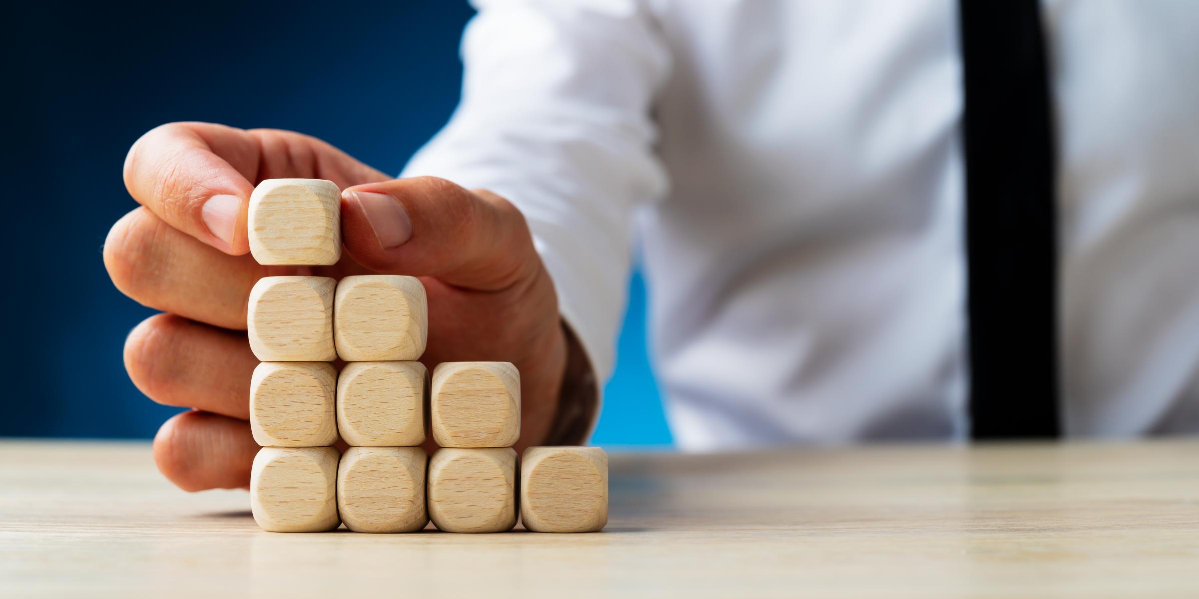 a hand building a pyramid of blocks