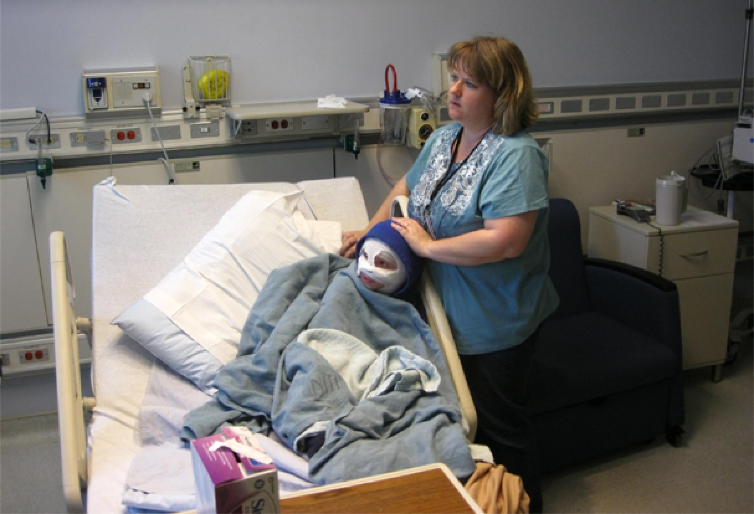 Mother comforts boy undergoing wet wrap treatment for eczema.