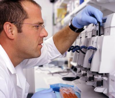 This photograph shows James Balow, Jr., M.S., biologist. He is inserting a GeneChip into the GeneChip fluidics station to analyze RNA from patient samples in order to identify genes that are differently expressed between patients with autoinflammatory diseases and controls.