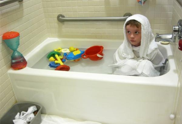 Photo of young boy wrapped in towels sitting in a bathtub
