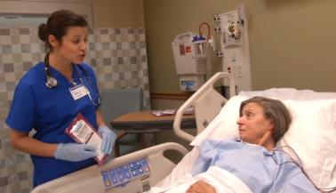 Healthcare worker speaking to patient in hospital bed