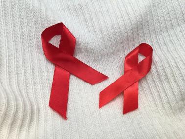 Red AIDS awareness ribbons on a white wool surface 