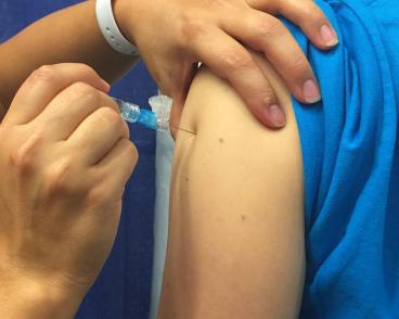 hand injects needle of syringe into shoulder muscle