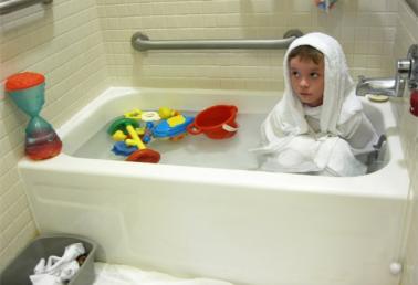 Photo of young boy wrapped in towels sitting in a bathtub