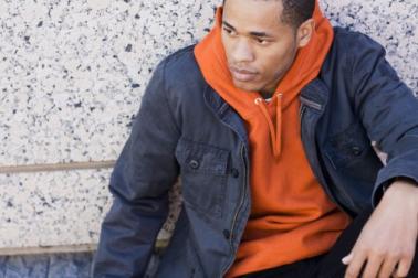 A photo of a man sitting against a wall.