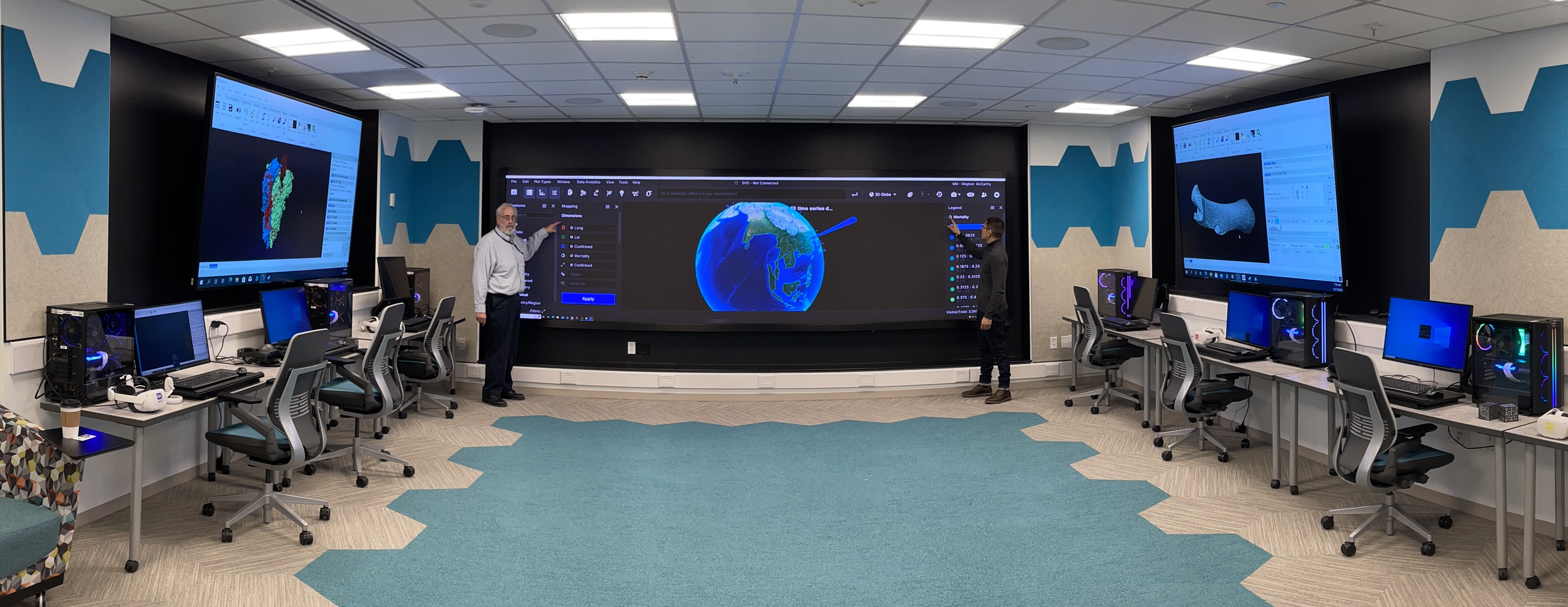 View of the NIAID Biovisualization Lab displaying 16-foot x 4.5-foot touch enabled video wall, two 98-inch 4k displays, and desktop computers equipped with high performance graphic cards.