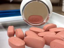 Antiretroviral drugs to treat HIV infection spill out of a pill bottle.
