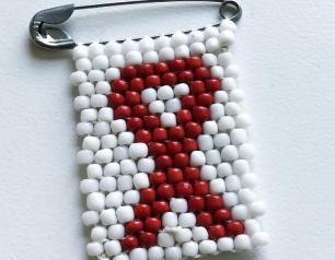 A white and red, beaded HIV awareness ribbon pin