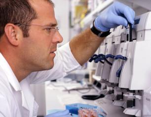 This photograph shows James Balow, Jr., M.S., biologist. He is inserting a GeneChip into the GeneChip fluidics station to analyze RNA from patient samples in order to identify genes that are differently expressed between patients with autoinflammatory diseases and controls.