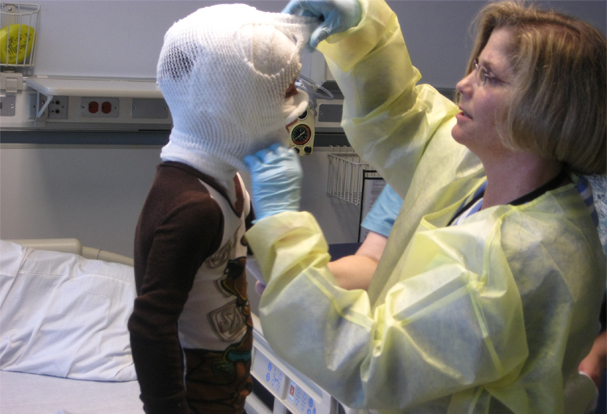 A wet wrap treatment being applied to face and head of young boy, an eczema patient at NIH.